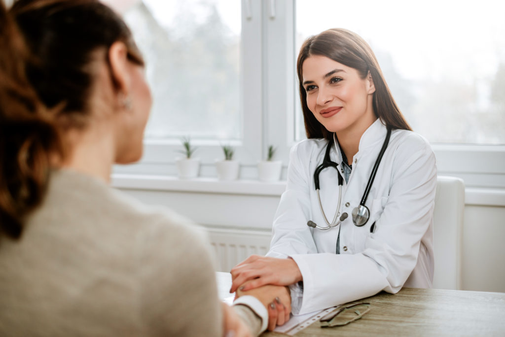 friendly female doctor holding female patients hand